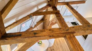 Ein Zimmer mit freiliegenden Holzbalken, weißen Wänden und einem weißen Tisch mit Stühlen.