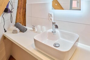A bathroom with a white sink, a mirror, and a towel on the counter. - fewo1846 - Ostwind - Vacation in a historic windmill with max. 4 persons (Flensburg)