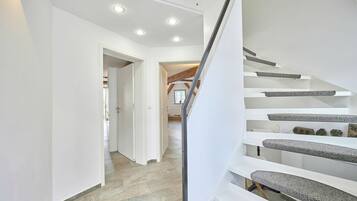 Ein modernes Interieur mit Treppe, weißen Wänden und Steinboden.