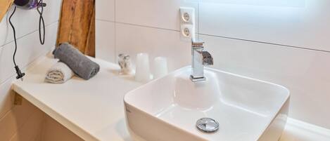 A bathroom with a white sink, a mirror, and a towel on the counter.