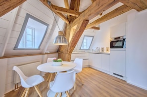Eine moderne Küche mit weißen Schränken, einem eingebauten Backofen und einer Essecke mit rundem Tisch und weißen Stühlen.