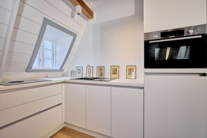 Eine moderne Küche mit weißen Schränken, einem eingebauten Ofen, einem Fenster mit Ausblick und gerahmten Bildern an der Wand.