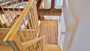 Eine Holztreppe mit Geländer, Holzboden und weißer Wand.