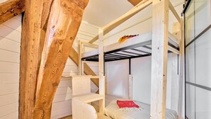 Dormitorio con literas, vigas de madera, un escritorio y una silla.