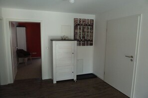A hallway with a white door, a red wall, and a white cabinet with drawers. - Holiday apartment with 2 bedrooms (Radolfzell)