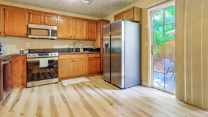 Une cuisine avec des meubles en bois, des appareils électroménagers en acier inoxydable et une grande fenêtre.