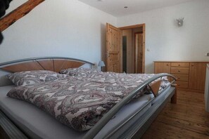 Ein Schlafzimmer mit Bett, Holzschrank und einer Tür zu einem anderen Raum.