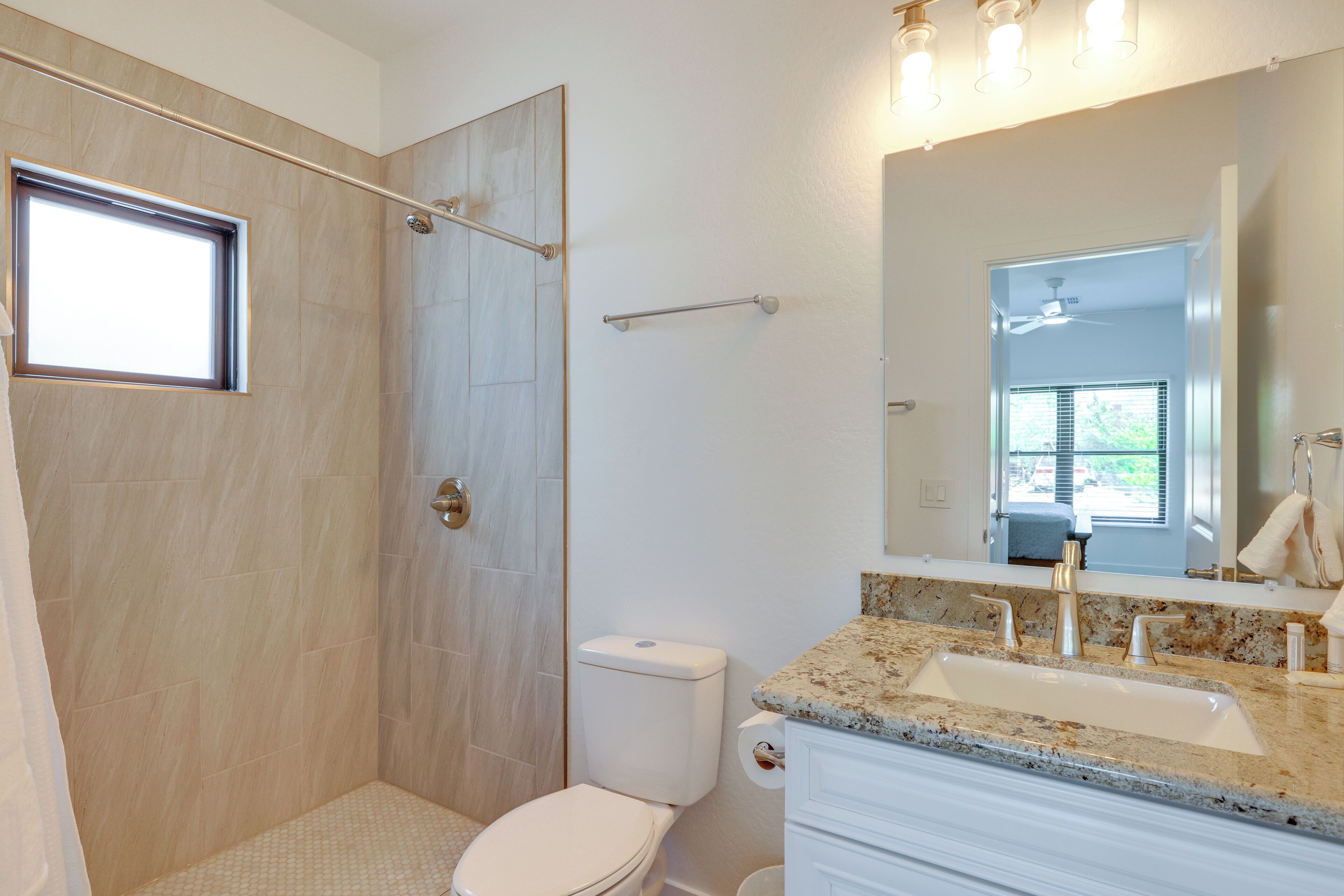 Une salle de bain équipée d’une douche, de toilettes, d’un lavabo et d’un grand miroir.
