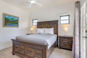 A bedroom with a wooden bed, two bedside tables, a ceiling fan, and a painting on the wall. - PHX Group Retreat By Dtwn! New Build w/ Patio (Phoenix)