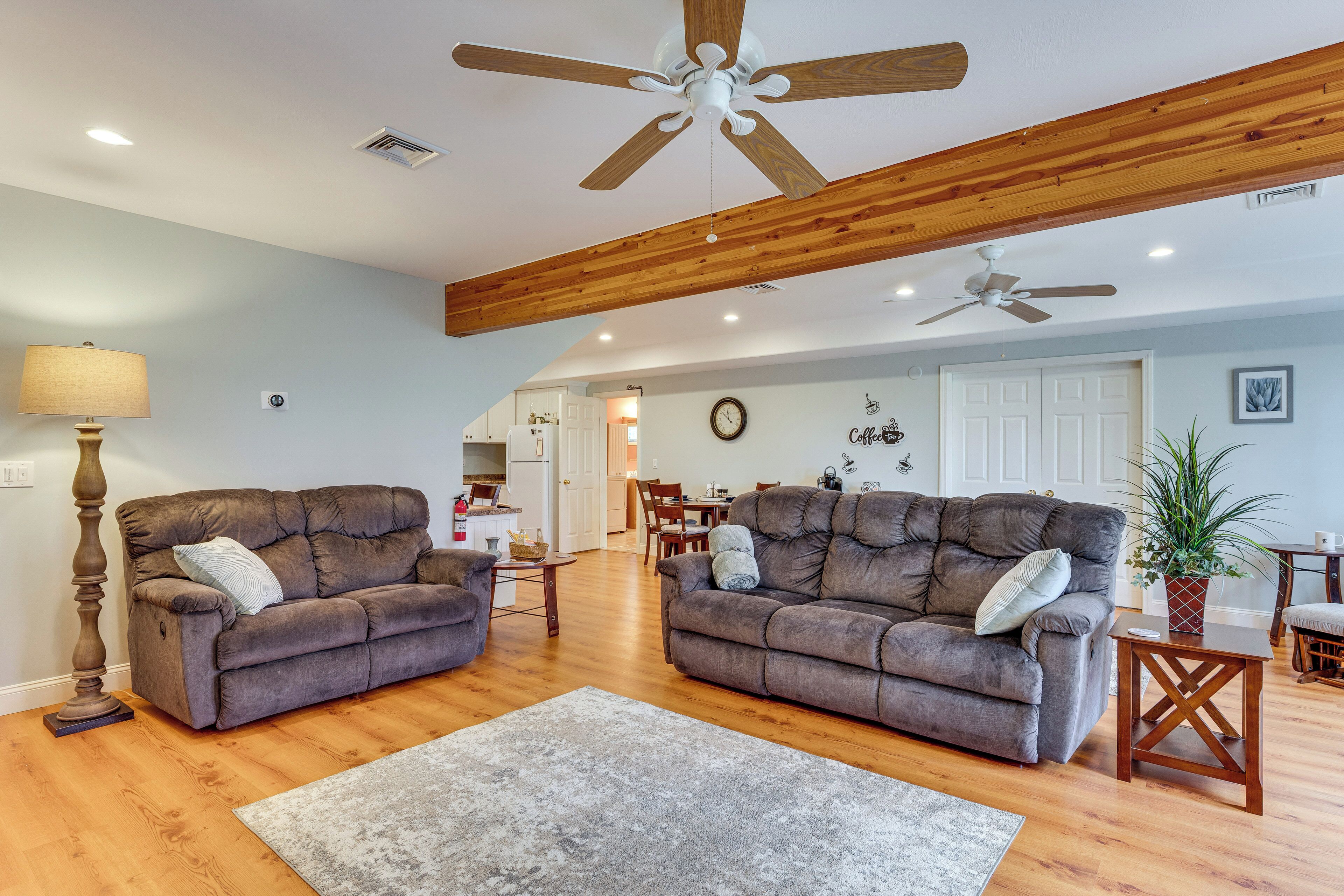 A spacious living room with two sofas, a coffee table, and a ceiling fan.