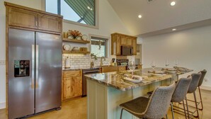 A modern kitchen with a large island, stainless steel appliances, and bar stools. - 'CopperTop Cabin' Waterfront White River Retreat (Norfork)