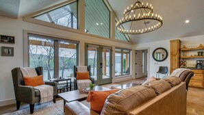 A spacious living area with a large sofa, armchairs, a coffee table, and a chandelier. - 'CopperTop Cabin' Waterfront White River Retreat (Norfork)