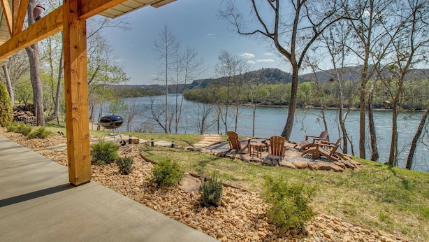 A covered patio with outdoor furniture, a grill, and a view of a lake surrounded by trees. - 'CopperTop Cabin' Waterfront White River Retreat (Norfork)