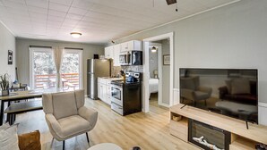 Ein modernes Wohnzimmer mit Flachbildfernseher, einer Couch, einem Sessel und einem Kamin.
