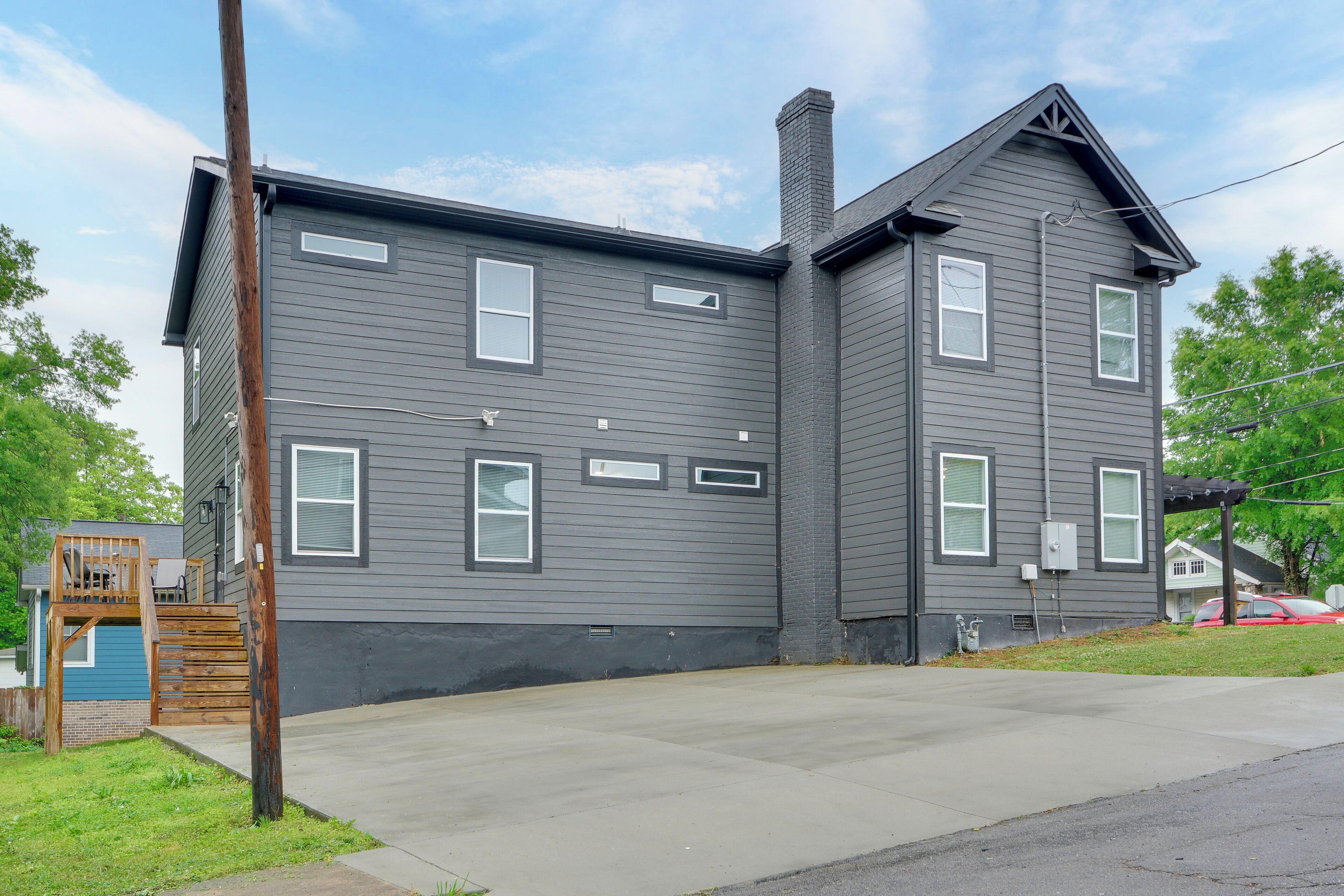 A two-story building with a gray exterior, a front porch, and a small wooden staircase leading to a deck.