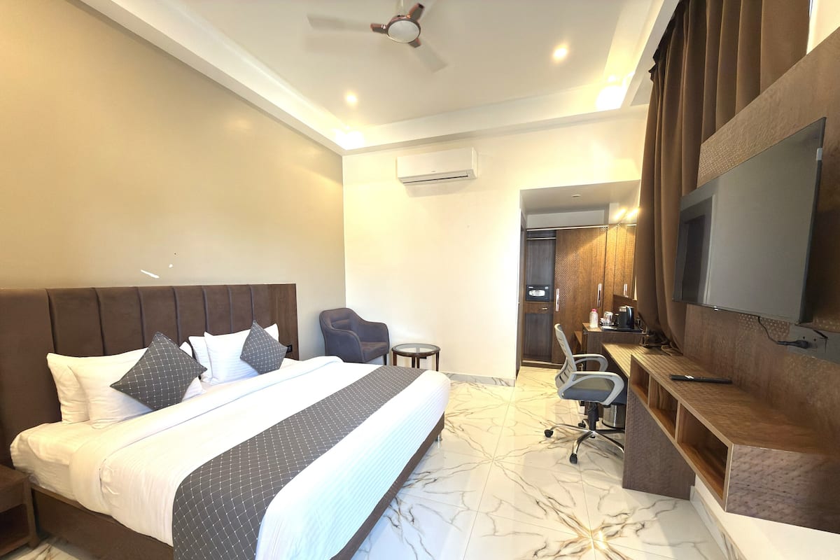 Una habitación de hotel con una cama, un escritorio, una silla, un televisor y un equipo de aire acondicionado.