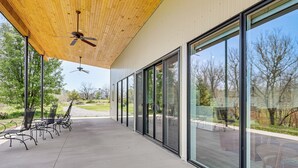 A covered outdoor area with a ceiling fan, large windows, and outdoor seating. - Mtn & Creek Views! Harrisonburg Escape on 10 Acres (Harrisonburg)