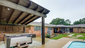 Un espacio al aire libre techado con un jacuzzi, una piscina y un patio con mesa y sillas.