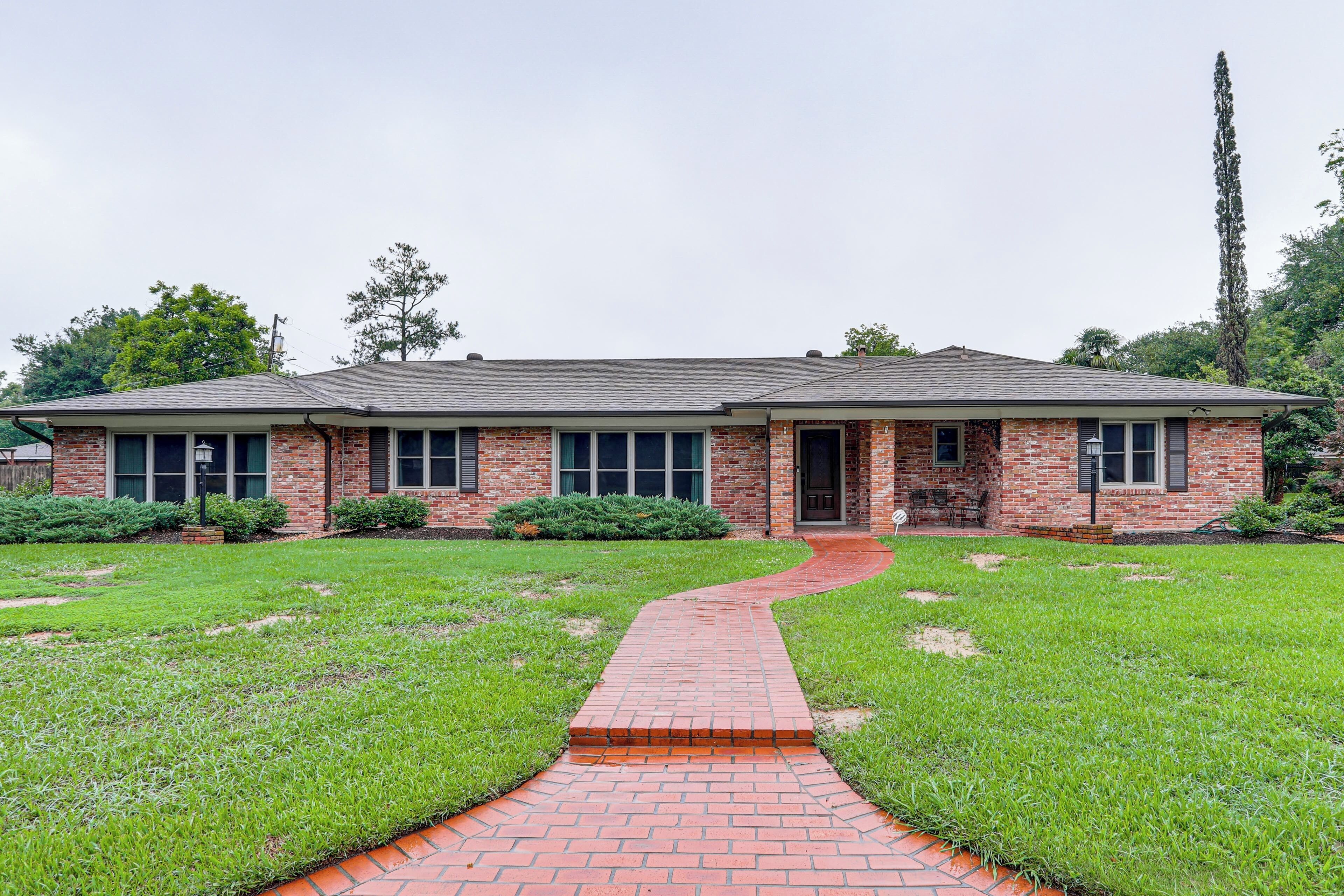 A single-story brick house with a front entrance, a brick pathway leading to the door, and a well-maintained lawn.