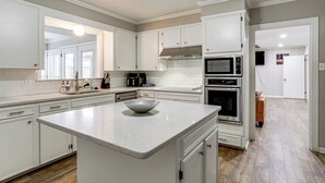 Una cocina moderna con armarios blancos, una isla central, un microondas y un horno.