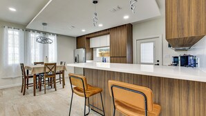 A modern kitchen with a central island, wooden cabinets, and a dining area with a table and chairs.
