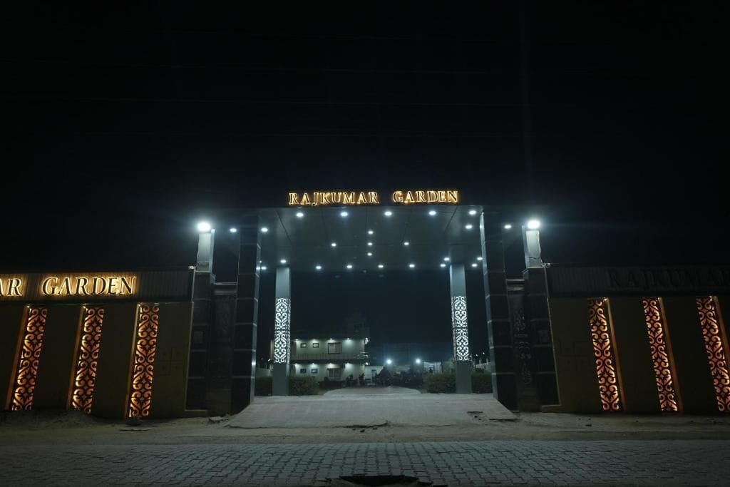 A gated entrance with 'RAJKUMAR GARDEN' signage, a paved pathway, and decorative panels.