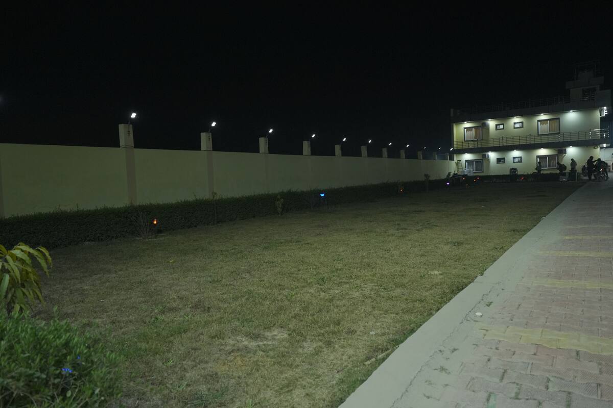 A building with multiple floors, a paved walkway, and a grassy area.
