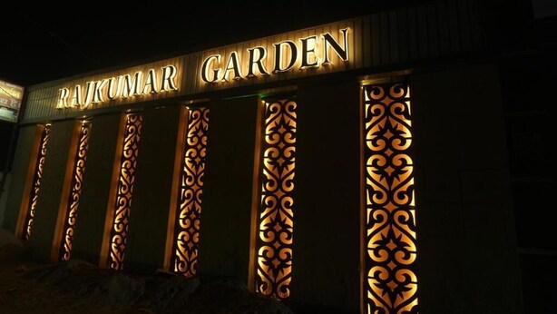 Un edificio con el nombre 'RAJKUMAR GARDEN' iluminado en la fachada.