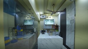 Una recepción con mostradores de mármol, dos monitores, ventiladores de techo y un cartel de salida.