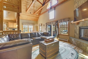 A spacious living room with a leather sectional sofa, a stone fireplace, and a rustic wooden ceiling. - Near Ponds, Hiking & Mtn Biking! Greenwood Cabin (Greenwood)
