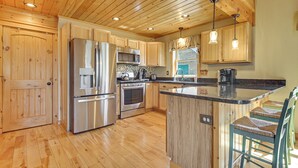 Una cocina con armarios de madera, electrodomésticos de acero inoxidable y una barra con taburetes.