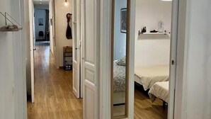 Um corredor com piso de madeira, paredes brancas e portas que dão para quartos.