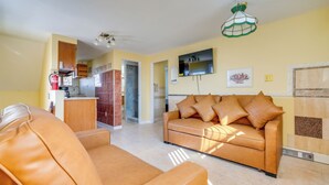 Una sala de estar con un sofá, una zona de cocina y una mesa de comedor.