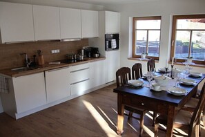 Una cucina moderna con mobili bianchi, un piano di lavoro in legno e un'area pranzo con tavolo imbandito per quattro persone.