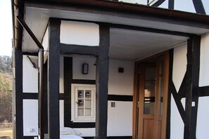 Un edificio tradizionale a struttura in legno e intonaco, con una porta in legno e una finestra.