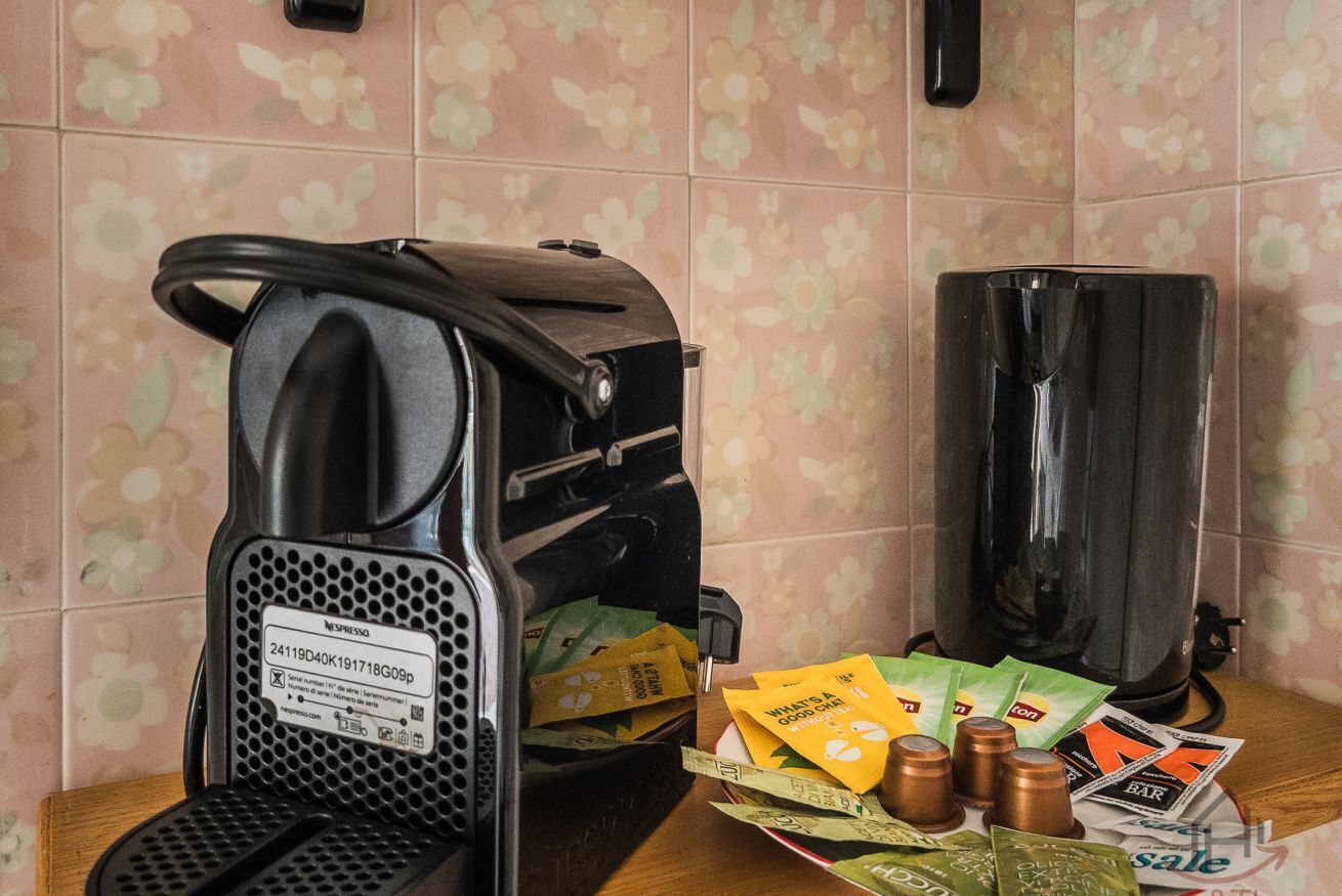 Eine Kaffeemaschine mit Auffangschale, einer Kaffeekanne und einer Schale mit Kaffeekapseln und Bargeld.