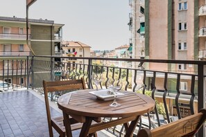 Ein Balkon mit Holztisch und -stühlen, einem Glas und einem Teller.