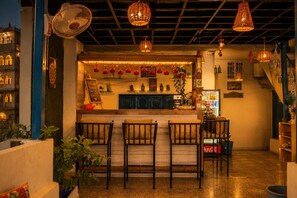 Una zona de bar con mostrador, asientos y elementos decorativos como luces colgantes y adornos en la pared.