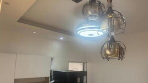 Una cocina moderna con un refrigerador negro, un salpicadero de mármol y una lámpara colgante original.