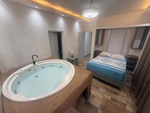 Ein Schlafzimmer mit Badewanne, Bett, Nachttisch und Deckenleuchte.