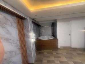 Une salle de bain moderne avec une baignoire sur pieds, des murs en marbre et un sol à carreaux.