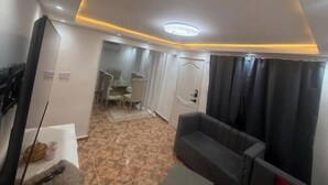 Un salon moderne comprenant un canapé, un téléviseur à écran plat et un coin repas avec une table et des chaises.