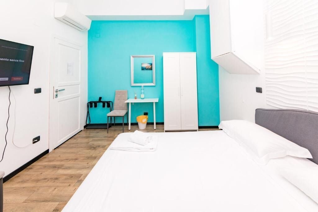 A hotel room with a bed, a desk, a chair, a wardrobe, and a television.