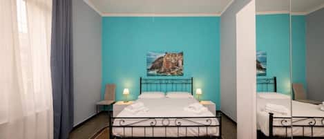 Ein Hotelzimmer mit einem Bett, zwei Nachttischen, einem Spiegel und einem Bild an der Wand.