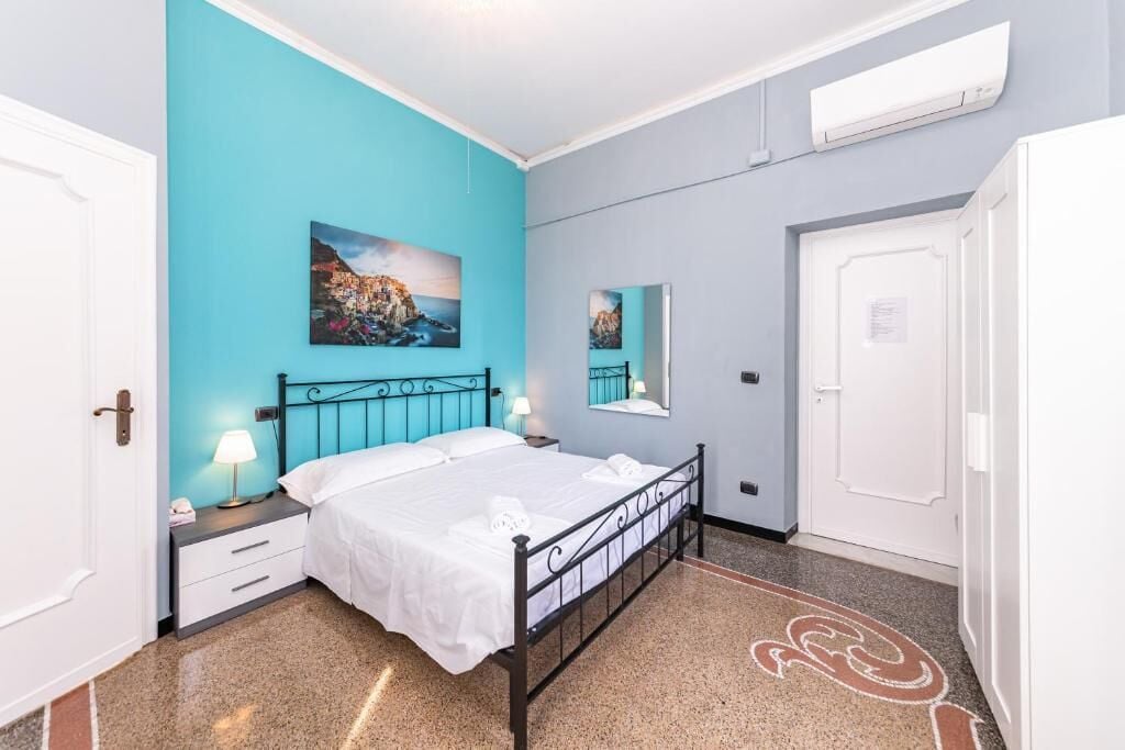 A bedroom with a bed, nightstands, a mirror, and artwork on the walls.