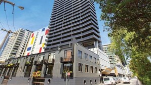 Un moderno edificio de gran altura con varios balcones, ventanas amplias y una combinación de estilos arquitectónicos.