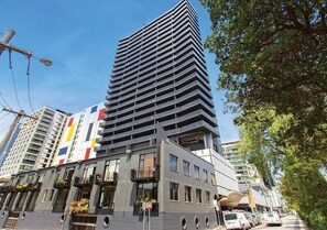 Ein modernes Hochhaus mit mehreren Balkonen, großen Fenstern und einer Mischung aus Baustilen.
