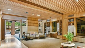 Un vestíbulo moderno con techo de madera, una recepción, una zona de estar y un ventanal grande.