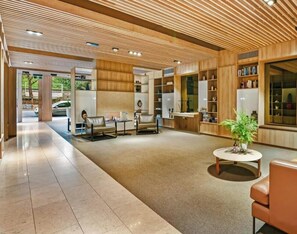 Eine moderne Lobby mit Holzboden, einer Rezeption, einer Sitzecke und einem großen Fenster.