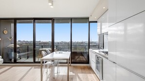 Una cocina moderna con un ventanal grande, una zona de comedor con mesa y sillas, y vistas a la ciudad.